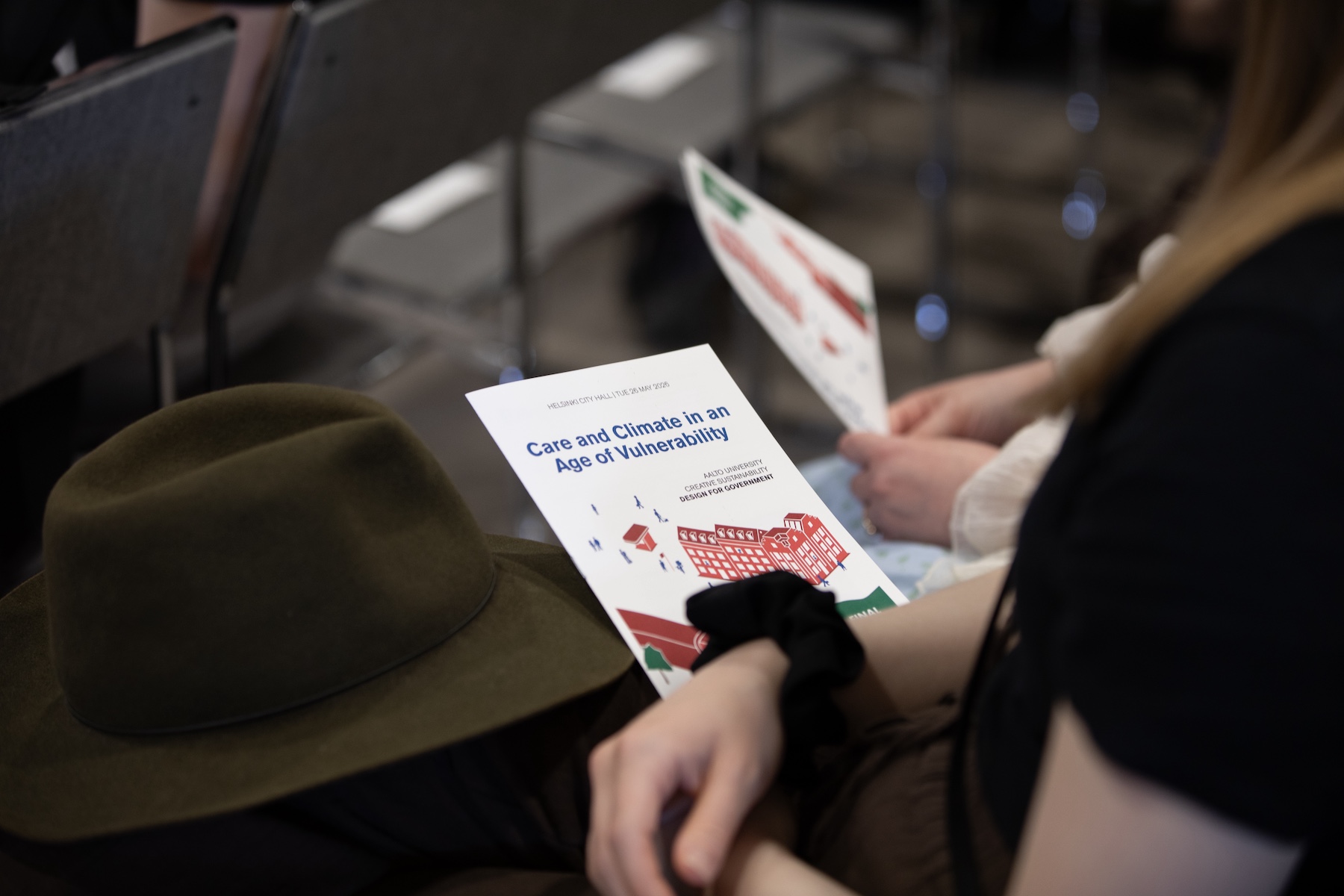 Event attendees sitting in chairs and holding flyers